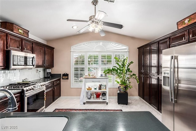 3938 Redfield Ave, North Las Vegas, NV 89032 - kitchen with appliances with stainless steel finishes, a ceiling fan, dark brown cabinets, decorative backsplash, and vaulted ceiling