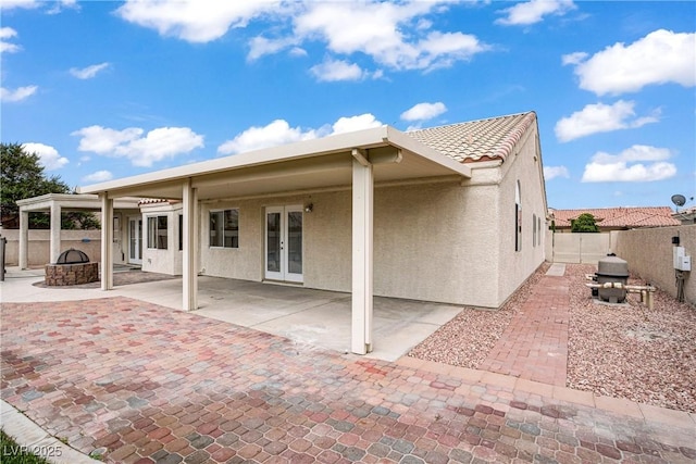 6125 Resort Ridge St, Las Vegas, NV 89130 - rear view of property with french doors, stucco siding, a fenced backyard, and an outdoor fire pit