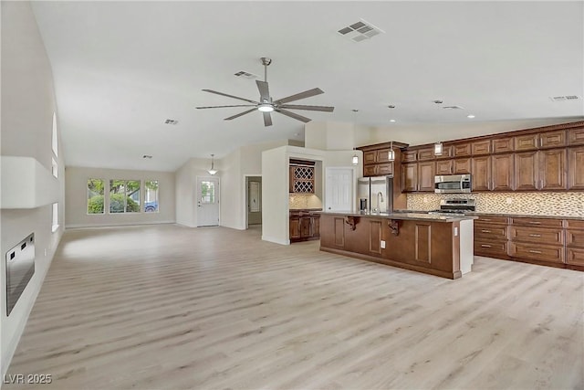 6125 Resort Ridge St, Las Vegas, NV 89130 - kitchen with stainless steel appliances, open floor plan, decorative backsplash, light wood-style floors, and a ceiling fan