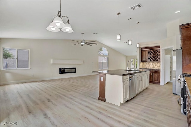 6125 Resort Ridge St, Las Vegas, NV 89130 - kitchen with stainless steel appliances, light wood-style floors, dark countertops, decorative backsplash, and vaulted ceiling