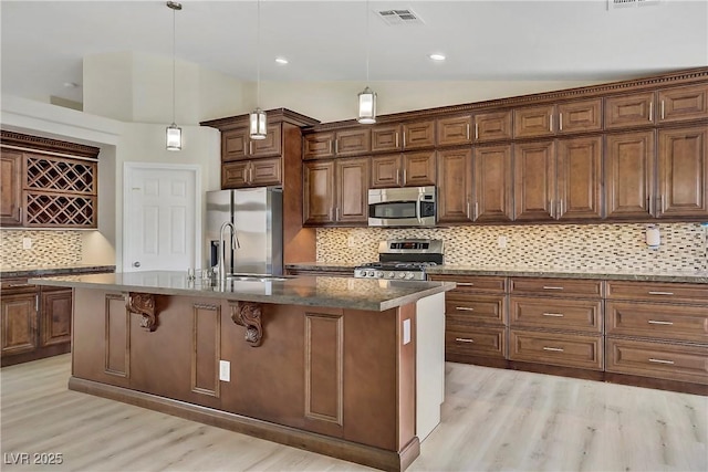 6125 Resort Ridge St, Las Vegas, NV 89130 - kitchen featuring stainless steel appliances, light wood-style flooring, vaulted ceiling, tasteful backsplash, and a kitchen bar