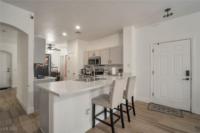 6388 Extreme Shear Ave Unit 103, Henderson, NV 89011 - kitchen featuring stainless steel microwave, a peninsula, a breakfast bar area, light wood-style floors, and recessed lighting