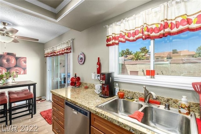 3393 Narod St, Las Vegas, NV 89121 - kitchen with stainless steel dishwasher, brown cabinets, light wood-style floors, ceiling fan, and light stone countertops