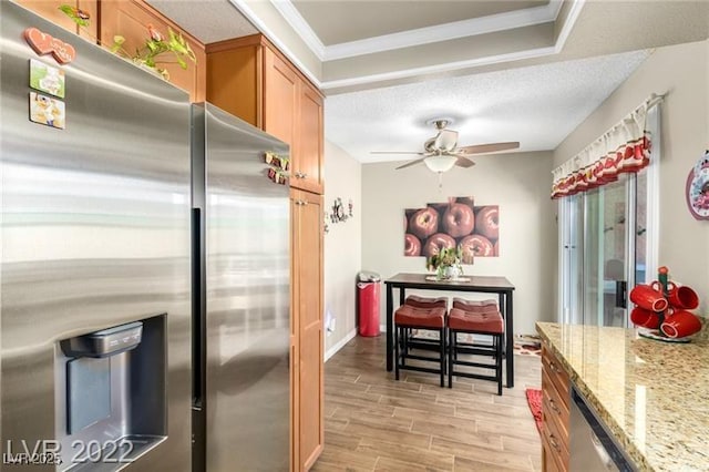 3393 Narod St, Las Vegas, NV 89121 - kitchen with stainless steel appliances, ceiling fan, light stone counters, light wood-type flooring, and brown cabinets