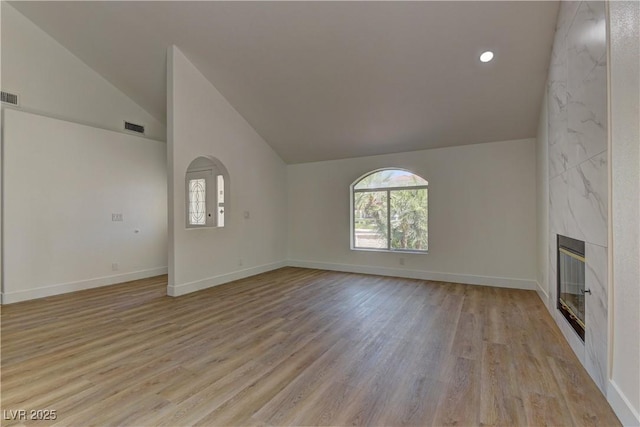 7629 Oyster Cove Dr, Las Vegas, NV 89128 - unfurnished living room featuring vaulted ceiling, plenty of natural light, a premium fireplace, light wood-type flooring, and recessed lighting