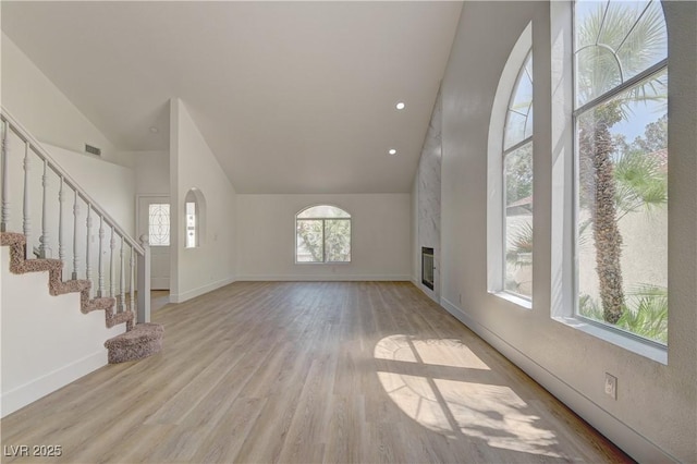 7629 Oyster Cove Dr, Las Vegas, NV 89128 - unfurnished living room featuring high vaulted ceiling, light wood finished floors, stairs, and a large fireplace
