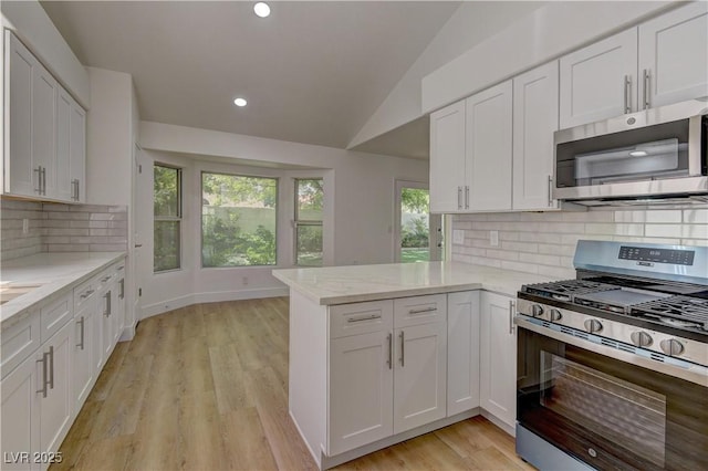 7629 Oyster Cove Dr, Las Vegas, NV 89128 - kitchen featuring stainless steel appliances, vaulted ceiling, white cabinets, a peninsula, and light stone counters