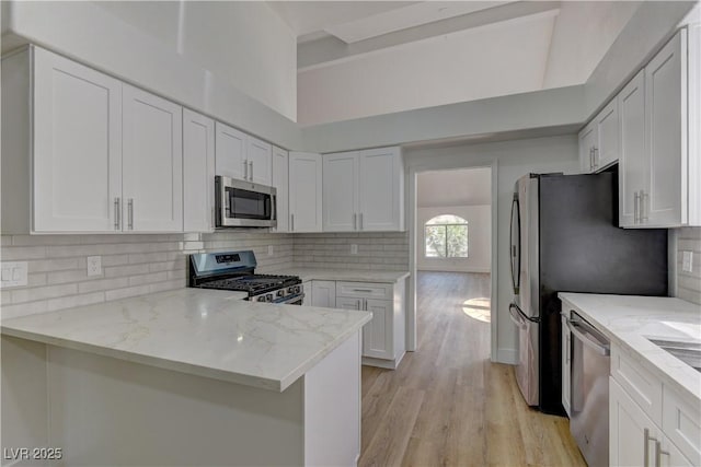 7629 Oyster Cove Dr, Las Vegas, NV 89128 - kitchen with appliances with stainless steel finishes, light wood-type flooring, light stone counters, decorative backsplash, and white cabinets