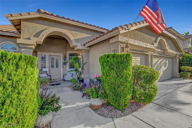 9553 Gainey Ranch Ave, Las Vegas, NV 89147 - property entrance featuring a garage, stucco siding, a tile roof, and concrete driveway