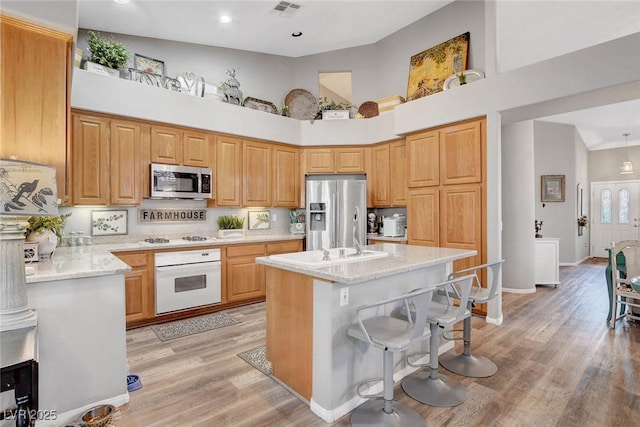 9553 Gainey Ranch Ave, Las Vegas, NV 89147 - kitchen with stainless steel appliances, high vaulted ceiling, a kitchen island, a kitchen bar, and light wood-style floors