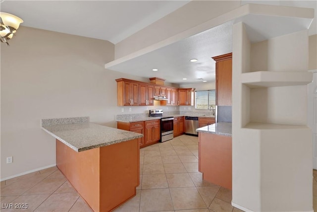 1770 W Charleston Park Ave, Pahrump, NV 89048 - kitchen featuring stainless steel appliances, a peninsula, brown cabinetry, under cabinet range hood, and light tile patterned floors
