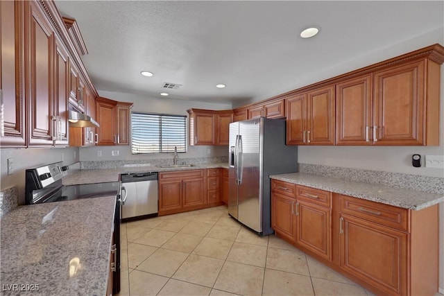 1770 W Charleston Park Ave, Pahrump, NV 89048 - kitchen with appliances with stainless steel finishes, brown cabinetry, under cabinet range hood, light stone countertops, and light tile patterned floors