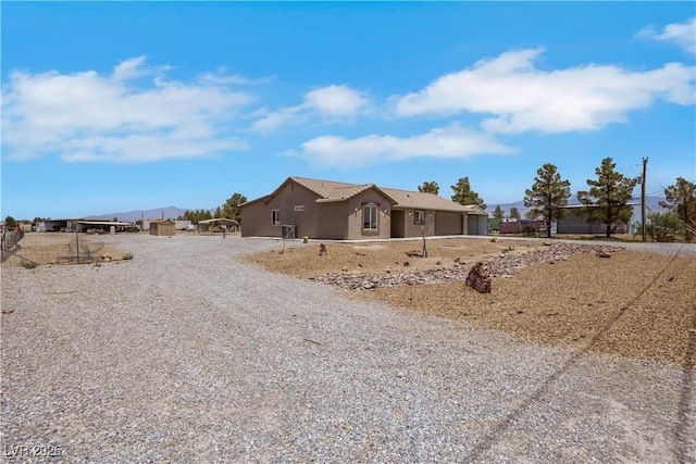 1770 W Charleston Park Ave, Pahrump, NV 89048 - view of front of property with a garage, gravel driveway, stucco siding, and a mountain view