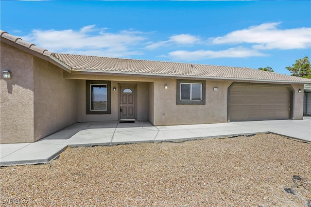 1770 W Charleston Park Ave, Pahrump, NV 89048 - view of front facade with stucco siding, a tiled roof, an attached garage, and concrete driveway