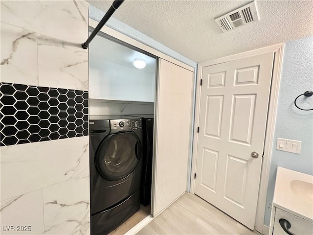 601 Cabrillo Cir Unit 1293, Henderson, NV 89015 - washroom featuring washer / clothes dryer, a textured ceiling, and light wood-style floors
