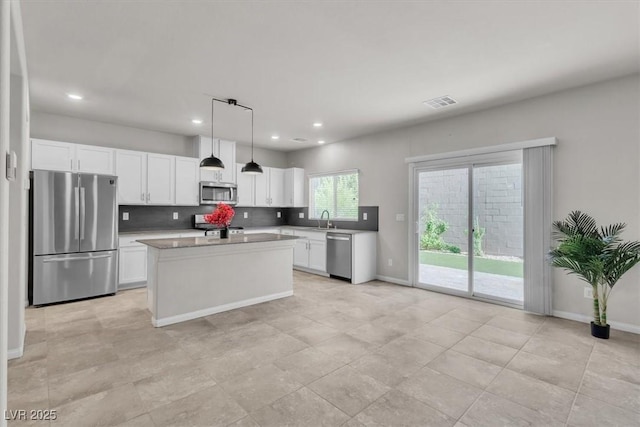 487 Via Renata, Henderson, NV 89044 - kitchen with appliances with stainless steel finishes, white cabinets, decorative backsplash, recessed lighting, and a center island
