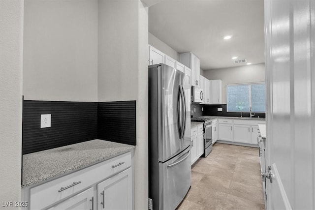 487 Via Renata, Henderson, NV 89044 - kitchen featuring appliances with stainless steel finishes, white cabinetry, tasteful backsplash, light stone countertops, and recessed lighting