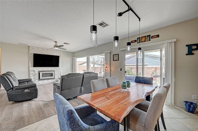 7460 Chaffinch St, North Las Vegas, NV 89084 - dining area with a ceiling fan, a stone fireplace, light tile patterned floors, and a textured ceiling