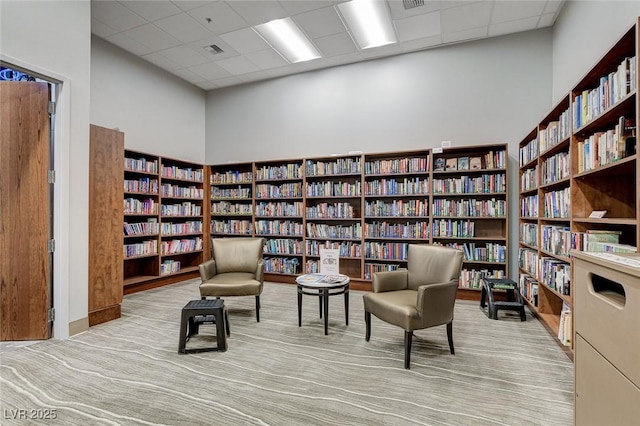 7460 Chaffinch St, North Las Vegas, NV 89084 - sitting room featuring wall of books, a paneled ceiling, and carpet flooring