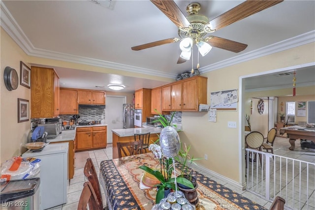 111 Narcissus Ln, Las Vegas, NV 89107 - kitchen featuring light countertops, decorative backsplash, light tile patterned floors, ceiling fan, and ornamental molding