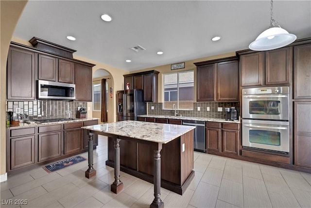 7125 Silver Ridge Peak St, Las Vegas, NV 89166 - kitchen featuring stainless steel appliances, arched walkways, decorative backsplash, dark brown cabinets, and recessed lighting