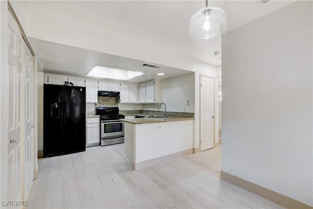 9409 Hershey Ln, Las Vegas, NV 89134 - kitchen featuring stainless steel range with gas cooktop, black fridge, light wood-style floors, and white cabinets