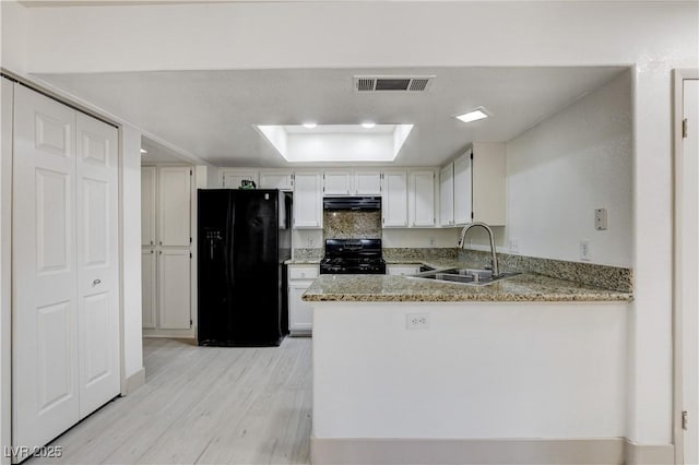 9409 Hershey Ln, Las Vegas, NV 89134 - kitchen with black appliances, a raised ceiling, extractor fan, light wood-style floors, and light stone countertops