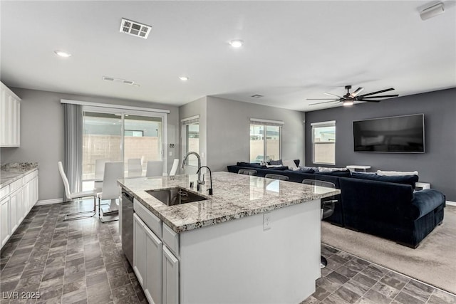 7615 Quail Dust St, North Las Vegas, NV 89084 - kitchen featuring stainless steel dishwasher, a ceiling fan, light stone countertops, an island with sink, and white cabinets