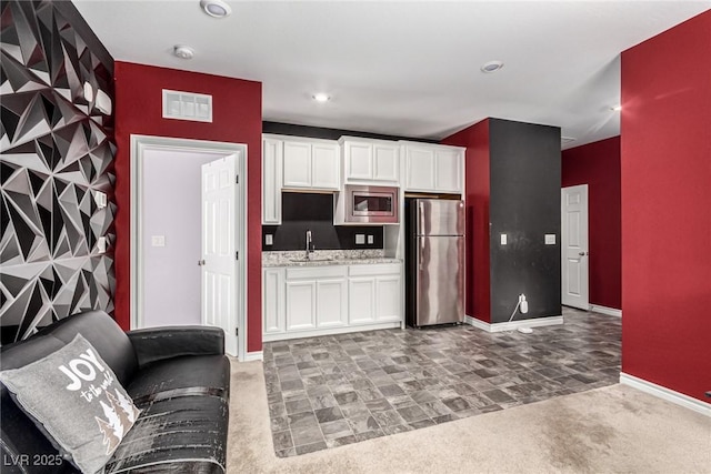 7615 Quail Dust St, North Las Vegas, NV 89084 - kitchen with stainless steel appliances, white cabinets, light carpet, recessed lighting, and light stone counters