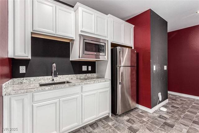 7615 Quail Dust St, North Las Vegas, NV 89084 - kitchen with stainless steel appliances, white cabinetry, and light stone counters
