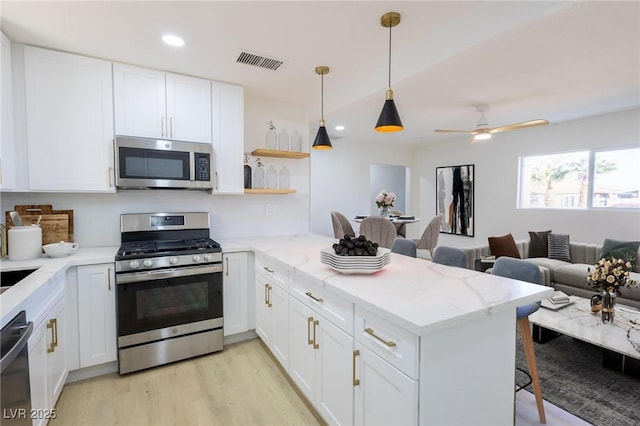 119 Cedar St, Henderson, NV 89015 - kitchen with stainless steel appliances, a peninsula, white cabinets, light wood-style flooring, and recessed lighting