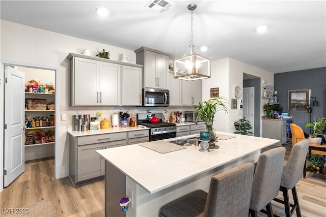 1981 Komodo Dragon Ct, North Las Vegas, NV 89032 - kitchen featuring stainless steel appliances, gray cabinets, a breakfast bar area, light countertops, and recessed lighting