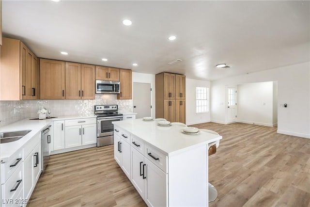 4616 Eureka St, Las Vegas, NV 89103 - kitchen with stainless steel appliances, light countertops, decorative backsplash, a kitchen island, and light wood-style floors