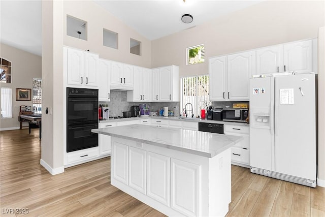 24 Staghorn St, Henderson, NV 89012 - kitchen featuring black appliances, a high ceiling, white cabinetry, backsplash, and a center island