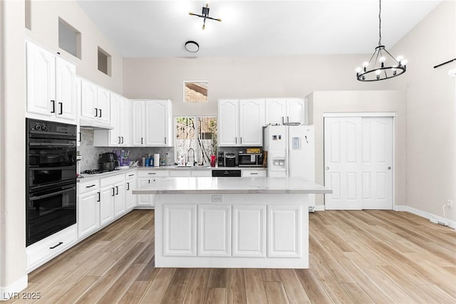 24 Staghorn St, Henderson, NV 89012 - kitchen with stainless steel microwave, a chandelier, white refrigerator with ice dispenser, light countertops, and a kitchen island