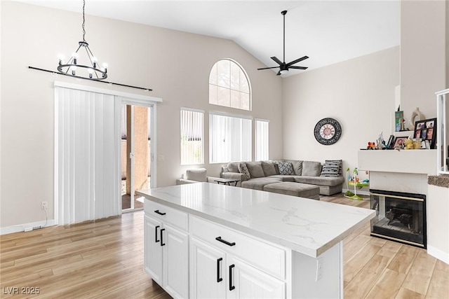 24 Staghorn St, Henderson, NV 89012 - kitchen with light wood finished floors, a chandelier, a ceiling fan, decorative light fixtures, and high vaulted ceiling