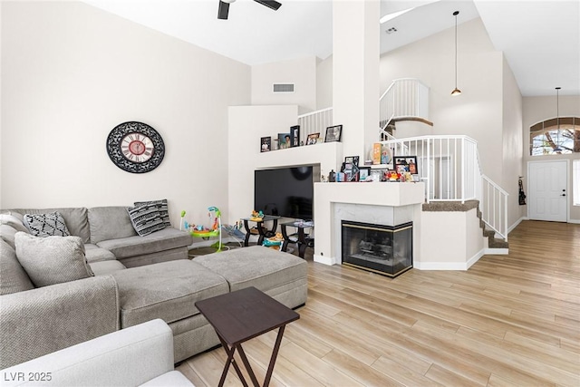 24 Staghorn St, Henderson, NV 89012 - living room with high vaulted ceiling, a ceiling fan, wood finished floors, stairs, and a tile fireplace