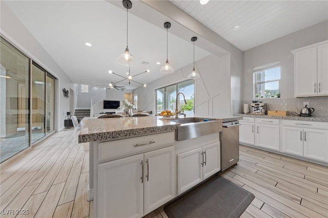 367 Pollino Peaks St, Las Vegas, NV 89138 - kitchen featuring stainless steel dishwasher, tasteful backsplash, wood finish floors, white cabinets, and open floor plan
