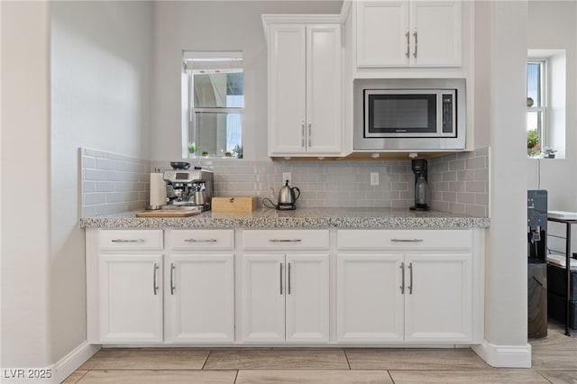 367 Pollino Peaks St, Las Vegas, NV 89138 - kitchen featuring stainless steel microwave, white cabinetry, healthy amount of natural light, and decorative backsplash