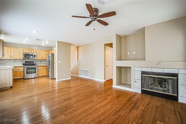 10204 Waseca Ave, Las Vegas, NV 89144 - unfurnished living room featuring a tiled fireplace, ceiling fan, and light wood-type flooring