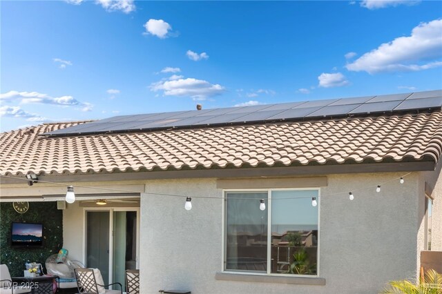 6209 Gambetta St, Las Vegas, NV 89115 - back of property featuring stucco siding, a tile roof, and roof mounted solar panels