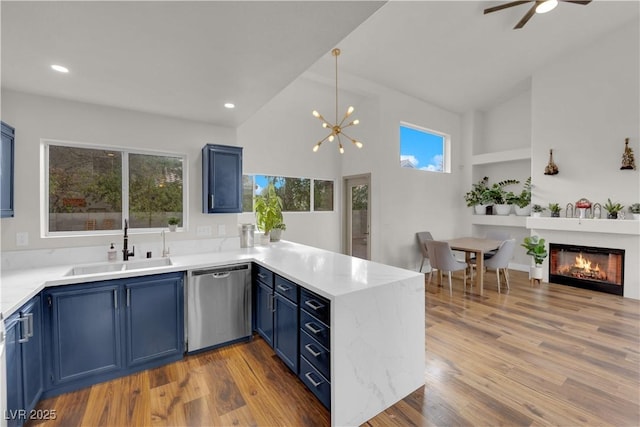9089 Harvest Season Ct, Henderson, NV 89074 - kitchen with dishwasher, blue cabinetry, a peninsula, high vaulted ceiling, and light wood-style floors