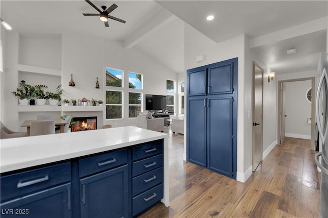 9089 Harvest Season Ct, Henderson, NV 89074 - kitchen featuring blue cabinetry, open floor plan, ceiling fan, wood finished floors, and a glass covered fireplace