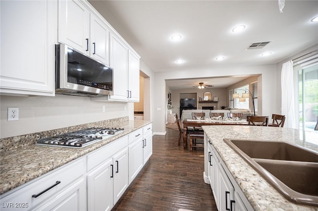 6937 Puetollano Dr, North Las Vegas, NV 89084 - kitchen featuring stainless steel microwave, gas stovetop, dark wood finished floors, recessed lighting, and white cabinetry