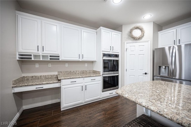 6937 Puetollano Dr, North Las Vegas, NV 89084 - kitchen with appliances with stainless steel finishes, white cabinetry, dark wood finished floors, recessed lighting, and light stone countertops