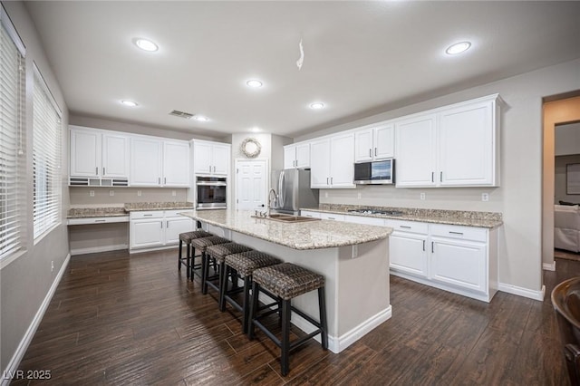 6937 Puetollano Dr, North Las Vegas, NV 89084 - kitchen with appliances with stainless steel finishes, a kitchen bar, white cabinets, dark wood-style flooring, and recessed lighting