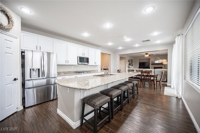 6937 Puetollano Dr, North Las Vegas, NV 89084 - kitchen featuring stainless steel appliances, a breakfast bar area, white cabinets, dark wood finished floors, and recessed lighting