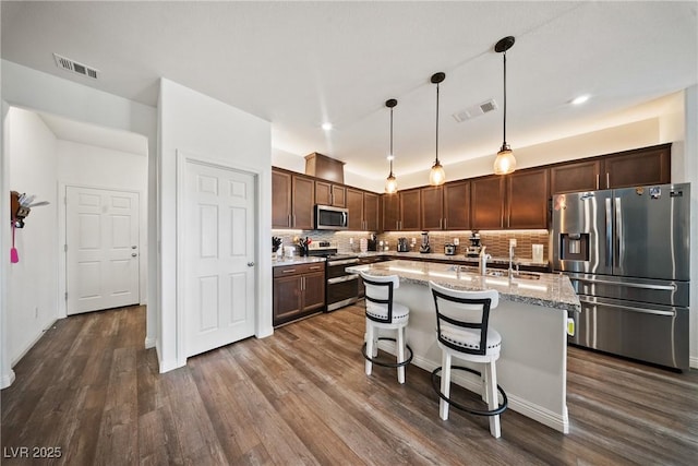 3603 E Umatilla Ave, Pahrump, NV 89061 - kitchen with appliances with stainless steel finishes, dark wood-style floors, tasteful backsplash, a kitchen island with sink, and recessed lighting