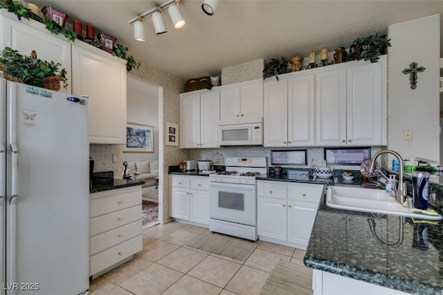7836 Silver Plateau Ave, Las Vegas, NV 89128 - kitchen featuring white appliances, white cabinetry, light tile patterned floors, tasteful backsplash, and dark stone counters