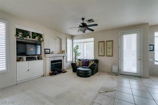7836 Silver Plateau Ave, Las Vegas, NV 89128 - carpeted living room featuring plenty of natural light, a ceiling fan, a tiled fireplace, and tile patterned floors